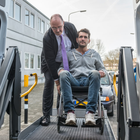 adult guy in the wheelchair assisted by the adult man