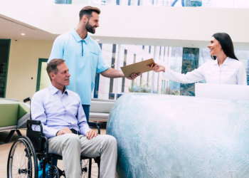 man in a wheelchair is moving in the hospital with help of medical special staff