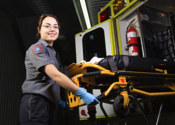 A paramedic person with his stretcher close to the ambulance.