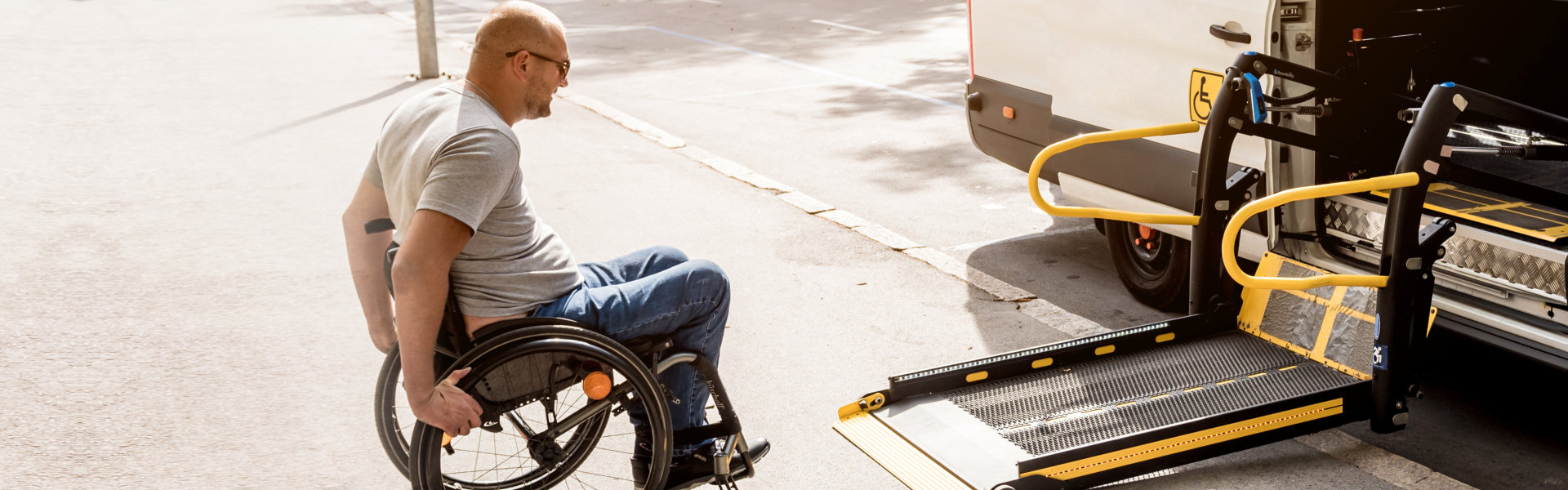 A man in a wheelchair moves to the lift of a specialized vehicle