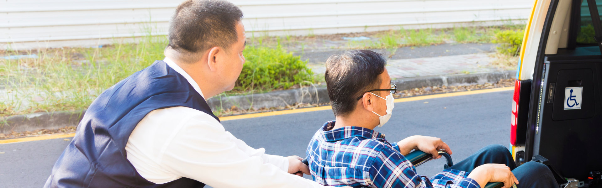 driver helping man on wheelchair getting into taxi