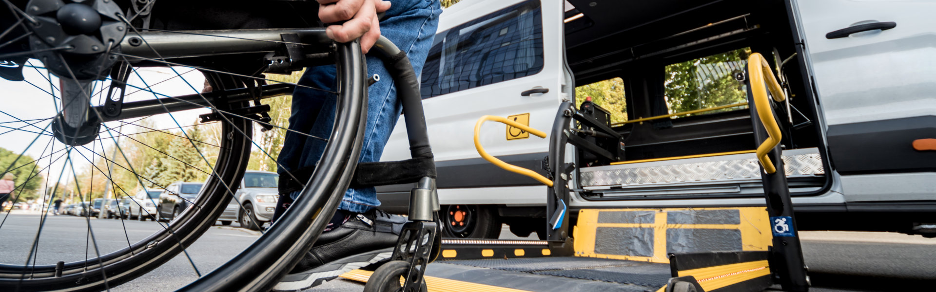 A man in a wheelchair moves to the lift of a specialized vehicle